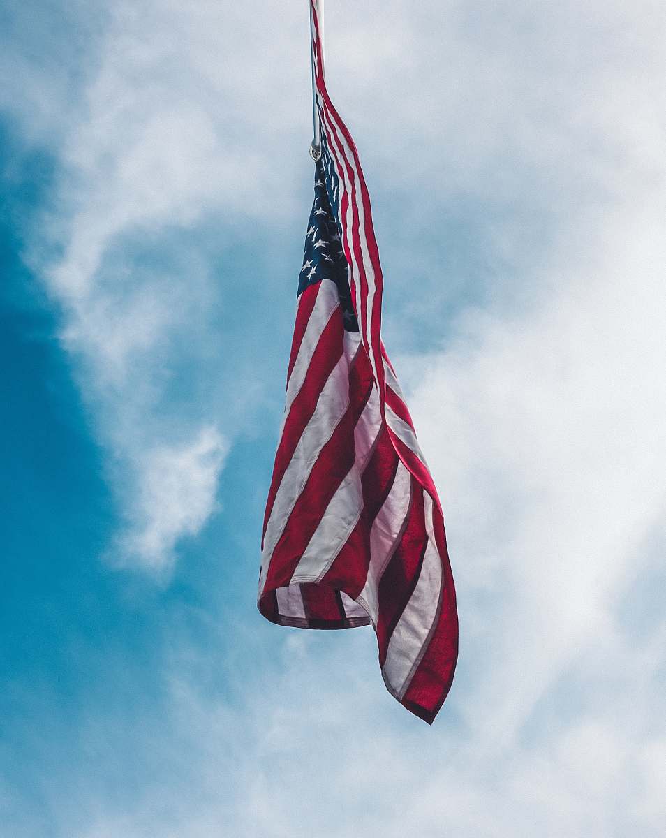 american flag flag of the United State flying under white clouds flag pole